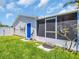Home's backyard featuring a screened-in porch, a blue door, and a well-maintained lawn at 1011 Coldstream Ct, Tarpon Springs, FL 34689