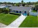 Charming home featuring lush lawn, lovely landscape, blue chairs, and a blue front door at 1011 Coldstream Ct, Tarpon Springs, FL 34689