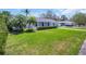 Charming home with a well-manicured lawn, palm trees, and a vibrant blue front door at 1011 Coldstream Ct, Tarpon Springs, FL 34689