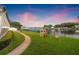 Waterfront backyard featuring lush green lawn, playset, and black metal fencing overlooking a scenic waterway at 1124 35Th Ne Ave, St Petersburg, FL 33704