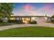 Charming single-story home with manicured lawn, mature landscaping, and a two-car garage at twilight at 1124 35Th Ne Ave, St Petersburg, FL 33704
