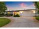 Charming single-story home with a well-manicured lawn, mature trees, and a two-car garage at dusk at 1124 35Th Ne Ave, St Petersburg, FL 33704