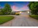 Charming single-story home with a well-manicured lawn, mature trees, and a two-car garage at dusk at 1124 35Th Ne Ave, St Petersburg, FL 33704
