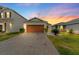 Single-story home with a well-manicured lawn and a brick-paved driveway at sunset at 11819 Brighton Knoll Loop, Riverview, FL 33579