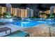 A beautiful community pool is surrounded by lounge chairs and tables at night at 1200 Country Club Dr # 5506, Largo, FL 33771