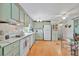 Bright kitchen with white appliances, light green cabinets, and wood laminate flooring at 123 Saint Kitts Way, Apollo Beach, FL 33572