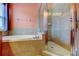 Bathroom showcasing a soaking tub and a glass-enclosed shower with tiled walls at 12628 White Bluff Rd, Hudson, FL 34669