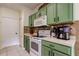 Well lit kitchen with white appliances, green cabinets, and tile backsplash at 12628 White Bluff Rd, Hudson, FL 34669