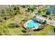 Aerial view of a pool, clubhouse, parking, and playground in a community setting by a pond at 12628 White Bluff Rd, Hudson, FL 34669