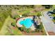 Aerial view of a clover-shaped pool, clubhouse, parking, and playground in a community setting at 12628 White Bluff Rd, Hudson, FL 34669