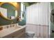 A modern bathroom with green walls, a gold-framed mirror, and a striped shower curtain at 12806 Castlemaine Dr, Tampa, FL 33626