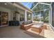 Relaxing screened-in patio featuring comfortable wicker furniture, a ceiling fan, and green scenery at 12806 Castlemaine Dr, Tampa, FL 33626