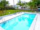 Gorgeous community swimming pool featuring crystal clear water surrounded by palm trees and lounge chairs at 1424 Ridge Shore Dr, Tarpon Springs, FL 34689