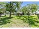 Large backyard with well-maintained lawn, mature trees, and screened-in pool area at 16214 W Course Dr, Tampa, FL 33624