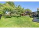 Lush green backyard showing manicured lawn, mature trees, and a screened lanai with covered patio at 16214 W Course Dr, Tampa, FL 33624