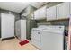 Functional laundry room with washer, dryer, storage cabinets and tile flooring at 16214 W Course Dr, Tampa, FL 33624