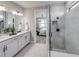 Well-lit bathroom with double vanity, granite countertop, and tiled shower with glass doors at 16305 Pebble Ridge Dr, Lakewood Ranch, FL 34211