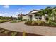 Inviting single-story home with brick driveway, lush landscaping, and welcoming covered porch at 16411 Sapphire Point Dr, Lakewood Ranch, FL 34211