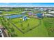 Aerial view of the neighborhood playground with blue shade and a basketball court surrounded by green grass and landscaping at 16415 Sapphire Point Dr, Lakewood Ranch, FL 34211