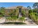 Elegant two-story home featuring a lush landscaped front yard with palm trees and a grand staircase at 2101 N Pointe Alexis Dr, Tarpon Springs, FL 34689