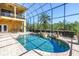 Beautiful screened-in pool area with a water feature, lush landscaping, and covered lanai at 2101 N Pointe Alexis Dr, Tarpon Springs, FL 34689