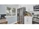 Kitchen with stainless steel refrigerator, white cabinets, marble backsplash, window, and wood-look floors at 2211 Belleair Rd # D3, Clearwater, FL 33764