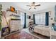 Bedroom with ceiling fan, rug, television, dresser and adjacent study nook with desk, chair and white window curtains at 2217 Stuart St, Tampa, FL 33605