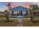 Charming single Gathering home featuring a screened-in front porch and mature trees under a sunset sky at 2217 Stuart St, Tampa, FL 33605