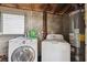 Practical laundry area featuring a modern washer and dryer, complemented by exposed wooden rafters and cement walls at 2217 Stuart St, Tampa, FL 33605