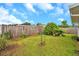 Spacious fenced backyard with grass and lush greenery under a blue sky with fluffy clouds at 2907 Mingo Dr, Land O Lakes, FL 34639