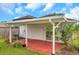 Covered red patio with white support posts, a sliding glass door and lush green grass nearby at 2907 Mingo Dr, Land O Lakes, FL 34639