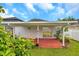 Covered red patio with white support posts with a view to a lush backyard at 2907 Mingo Dr, Land O Lakes, FL 34639
