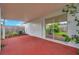Covered patio with red concrete flooring, access to the backyard and sliding glass door at 2907 Mingo Dr, Land O Lakes, FL 34639
