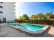 Community pool surrounded by pavers, hedge and building with view of mature trees at 30 Turner St # 202, Clearwater, FL 33756