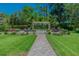 Landscaped backyard with a stone walkway leading to a pergola framed by manicured greenery at 3585 Torino Ln, Palm Harbor, FL 34683