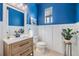 Stylish powder room features blue walls, white wainscoting, and modern vanity at 3585 Torino Ln, Palm Harbor, FL 34683