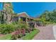 Close up of building with stone accents surrounded by colorful flower beds and lush greenery at 3585 Torino Ln, Palm Harbor, FL 34683