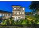 Elegant three-story home featuring multiple balconies and beautifully landscaped grounds at twilight at 3585 Torino Ln, Palm Harbor, FL 34683
