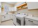 Efficient laundry room featuring modern washer and dryer units, ample counter space, and floating shelves at 3585 Torino Ln, Palm Harbor, FL 34683