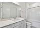 Bright bathroom featuring a single vanity, large mirror, white cabinets, and tub with white tile surround at 37202 Clinch Cir, Zephyrhills, FL 33540