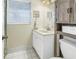 Well-lit bathroom with white tile floor, window, vanity, and wood cabinet at 3753 Hollow Oak Pl, Land O Lakes, FL 34639