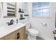 Updated bathroom with white sink and toilet, wood-look vanity, and stylish mirror at 3753 Hollow Oak Pl, Land O Lakes, FL 34639