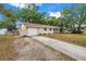 Side view of the home featuring a gravel driveway, one-car garage, and a quaint covered porch with a swing at 3753 Hollow Oak Pl, Land O Lakes, FL 34639