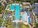 Expansive aerial view of a community pool area with a slide, a lap pool, and ample lounging space under palm trees and umbrellas at 4220 Barletta Ct, Wesley Chapel, FL 33543