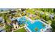 Stunning aerial view of a community pool with multiple slides and a lap pool surrounded by lush landscaping and palm trees at 4220 Barletta Ct, Wesley Chapel, FL 33543