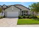 Well-maintained single-story home with stone accents, a two-car garage, brick paver driveway, and green lawn at 4220 Barletta Ct, Wesley Chapel, FL 33543