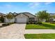 Single-story home boasts stone accents, a well-kept lawn, paver driveway, and vibrant landscaping at 4220 Barletta Ct, Wesley Chapel, FL 33543