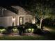 Inviting front entrance with stone accents, lush landscaping, and elegant glass front door lit at night at 4220 Barletta Ct, Wesley Chapel, FL 33543