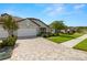 Attractive single-story home featuring a three-car garage, stone detailing, neat landscaping, and a brick driveway at 4220 Barletta Ct, Wesley Chapel, FL 33543
