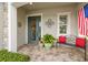 Welcoming front porch features a decorative door, brick pavers, and comfortable bench seating with vibrant red pillows at 4220 Barletta Ct, Wesley Chapel, FL 33543